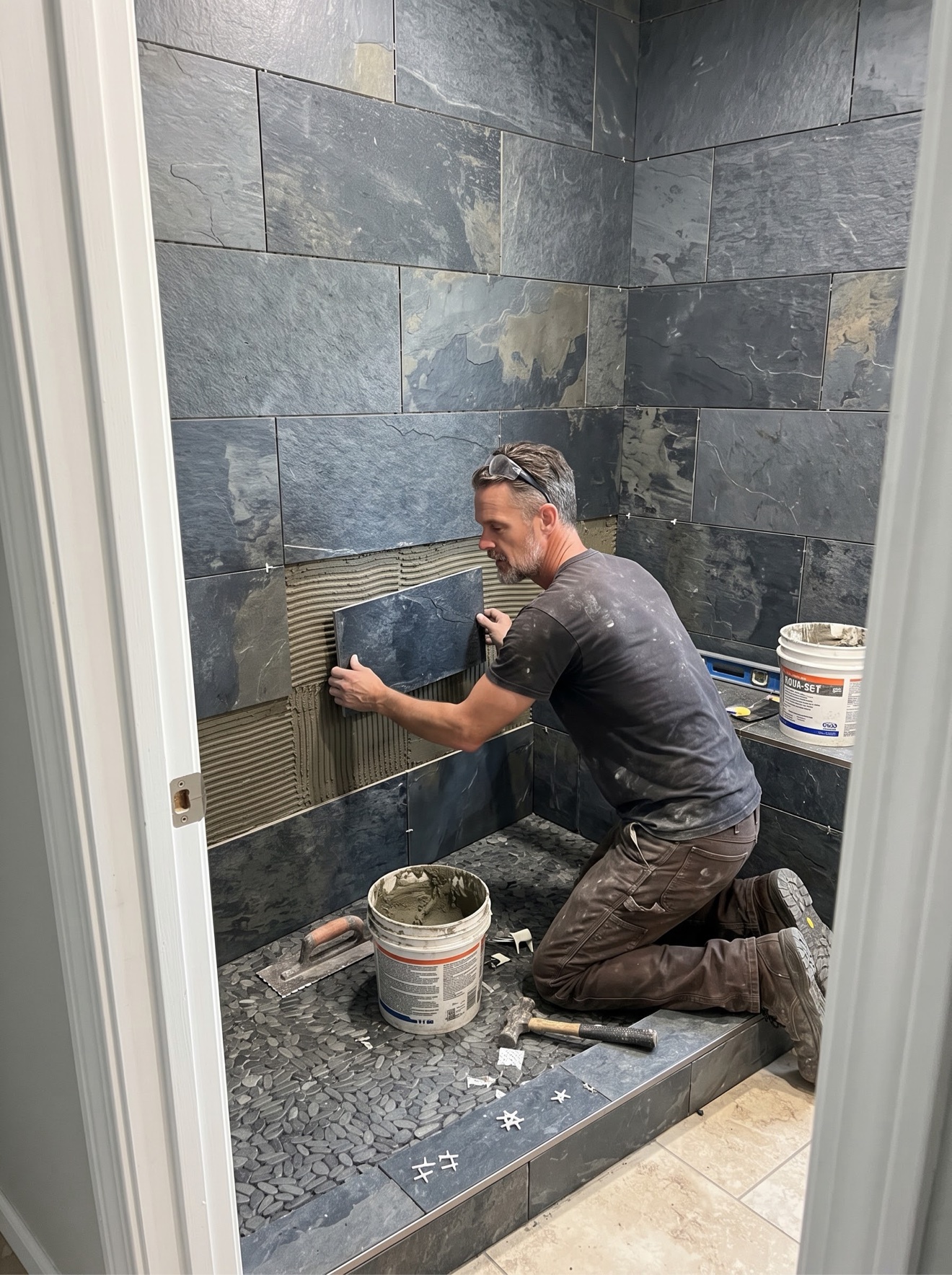 Simon Beames hand-setting a slate shower wall in Colorado Springs